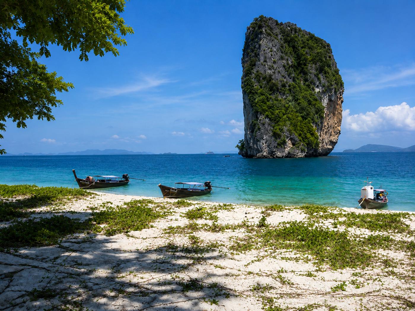 Limestone karst island and longtail boat in a turquoise bay